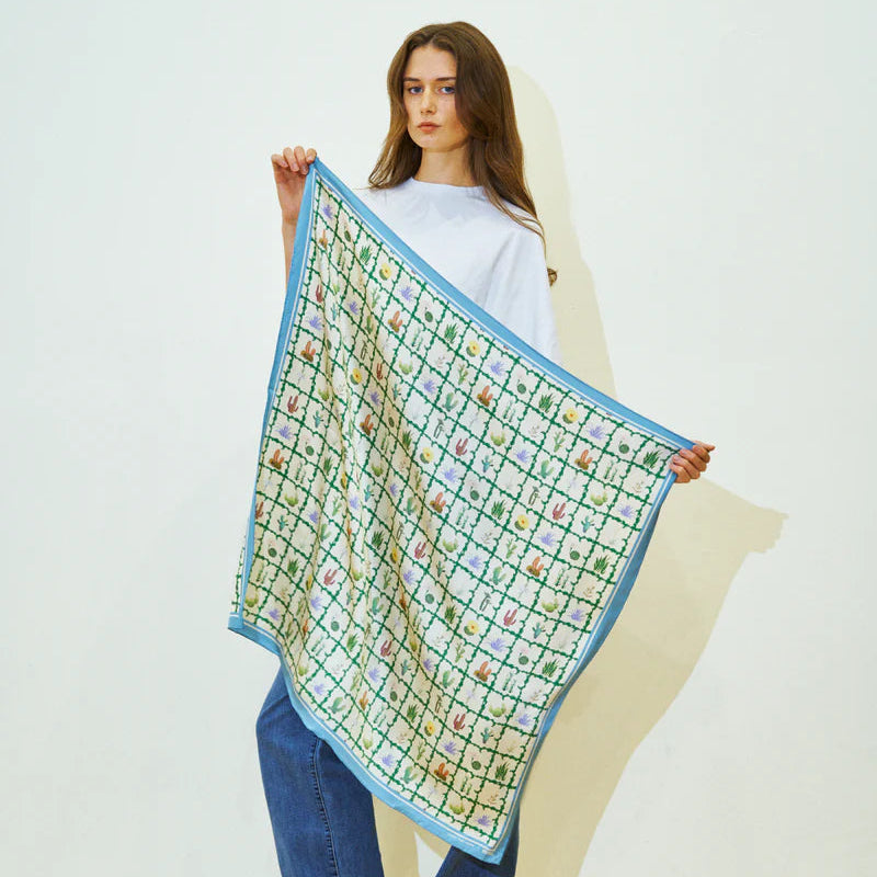 Woman holding a patterned scarf against a white background
